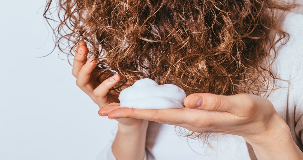 Imagem de uma mão com mousse de passar no cabelo